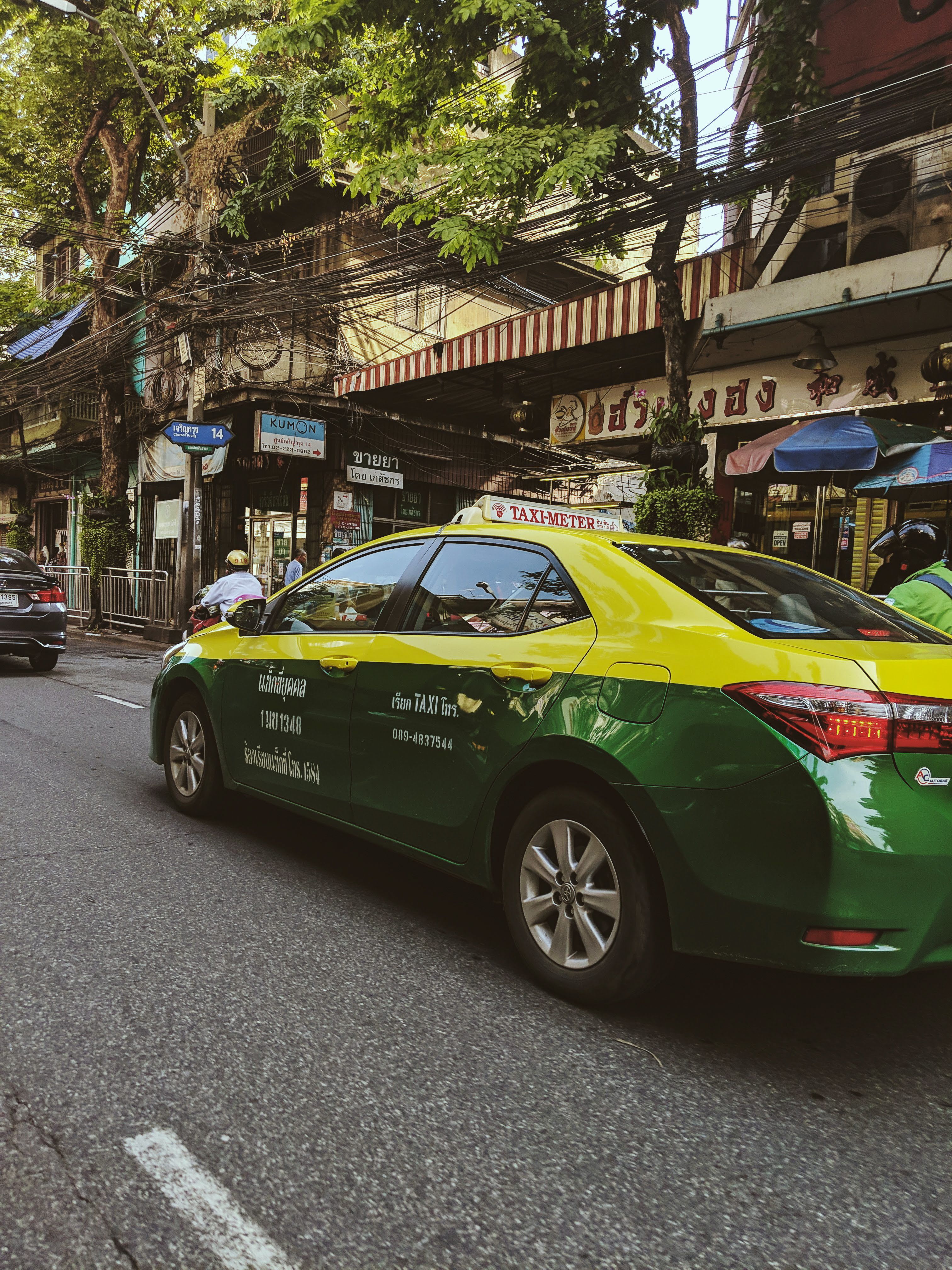 A line of taxis or a songthaew pickup truck in a Thai town