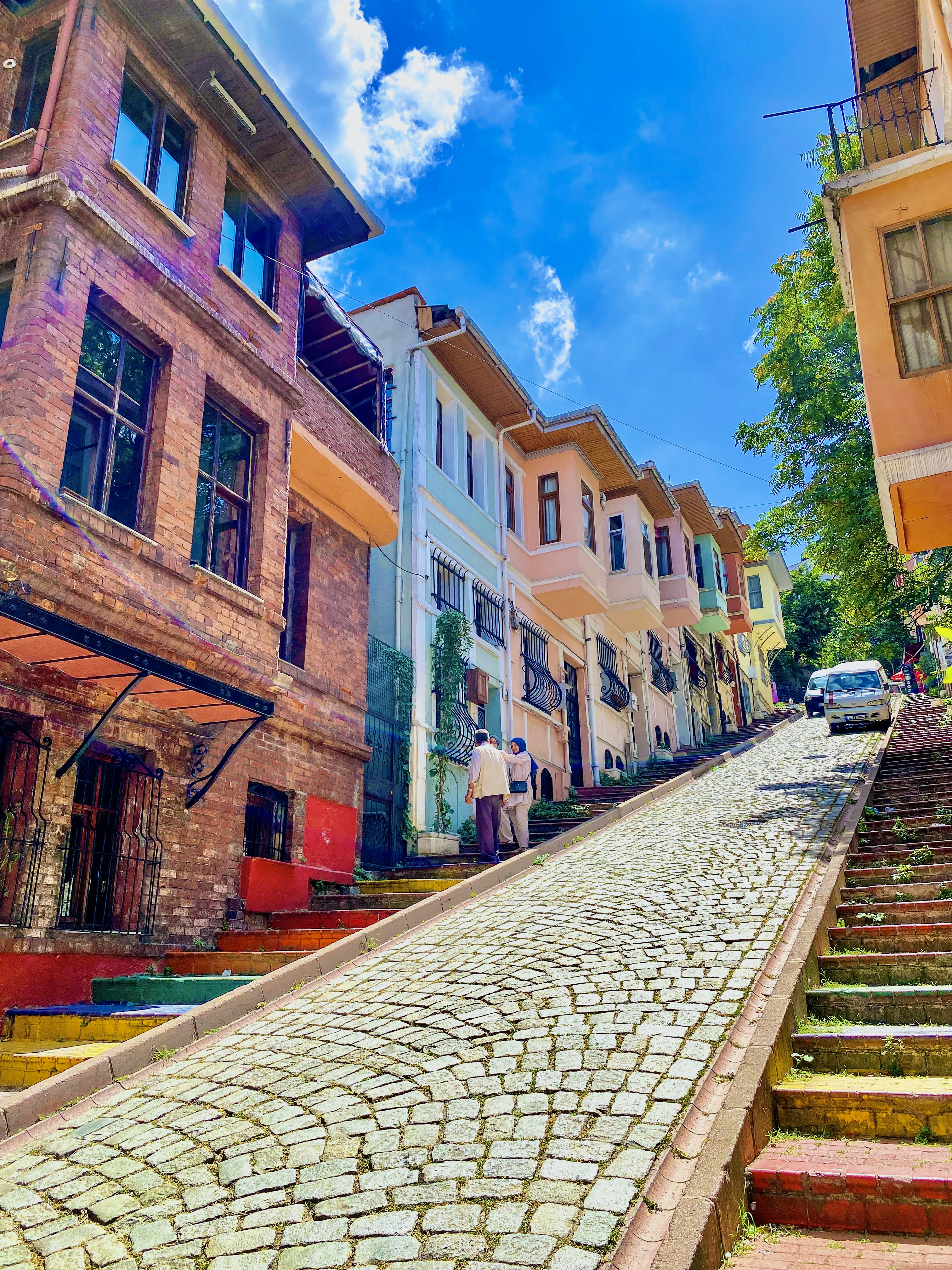 A narrow, colorful street in Balat or Karaköy with cafes and hanging lights