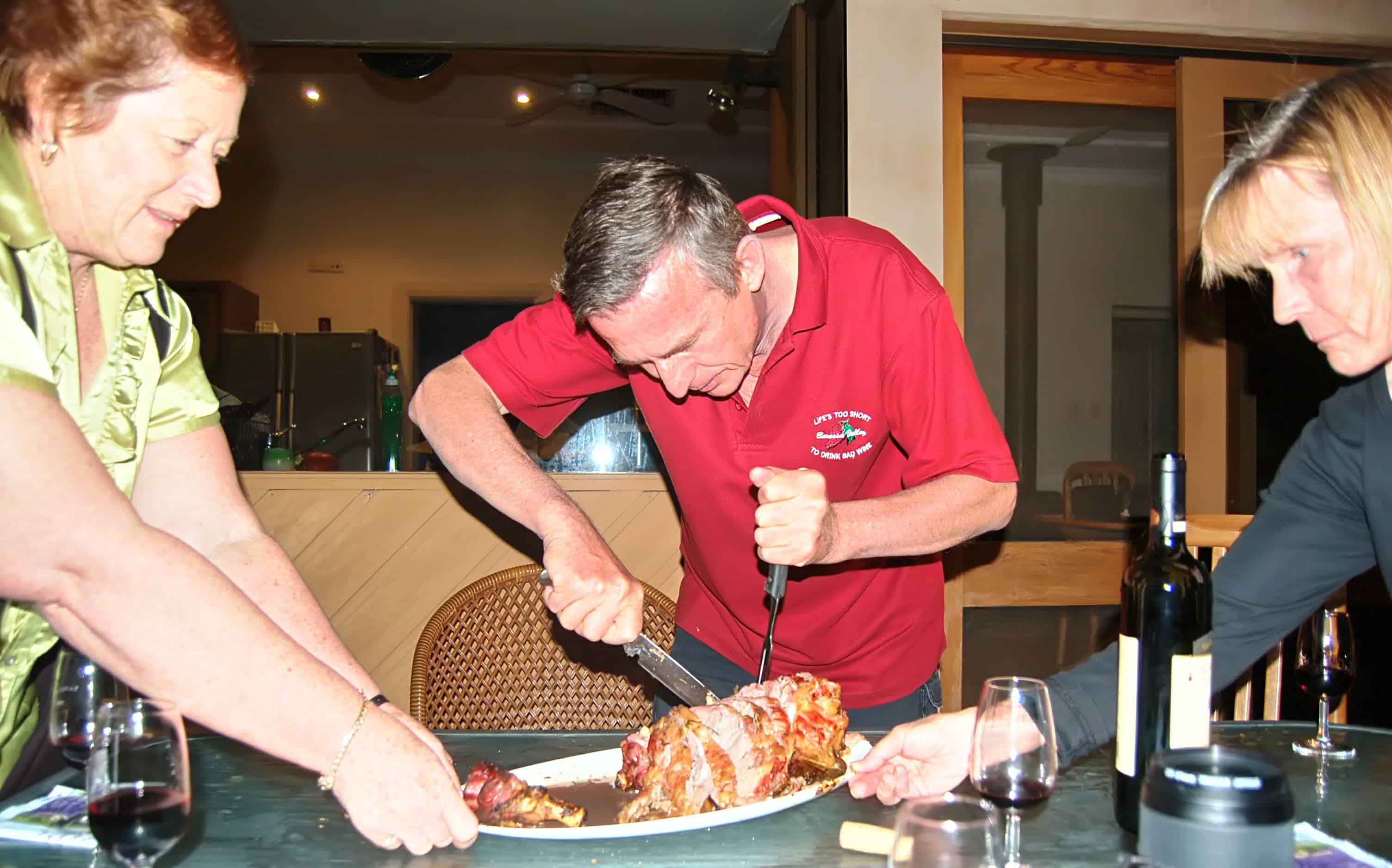 Jim Being helped by Leslie and Pam cuts the lamb