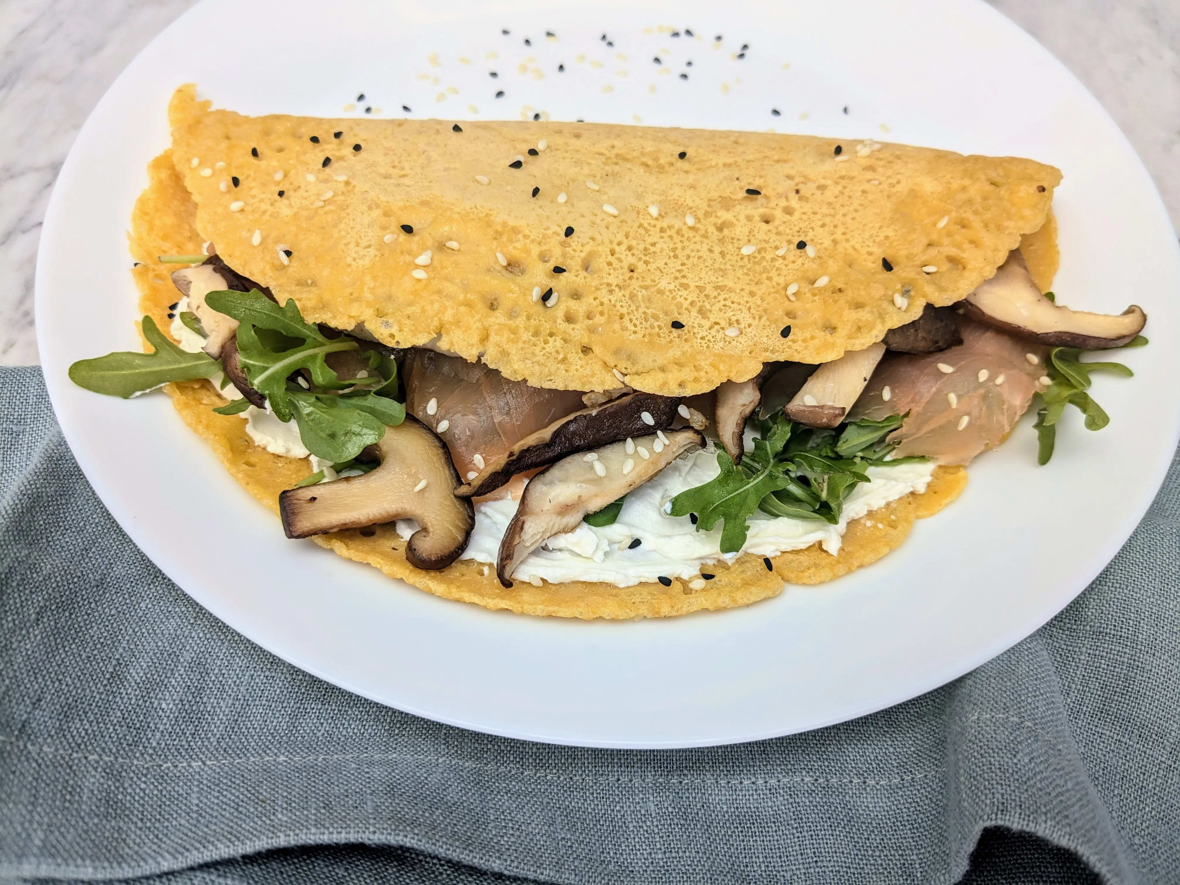 Photo of Socca (chickpea) pancakes with salmon, mushrooms and arugula