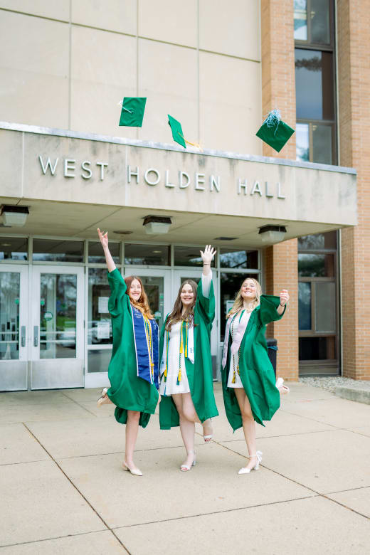 Three graduates tossing their caps