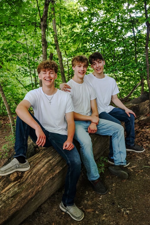 Three brothers sitting on a log