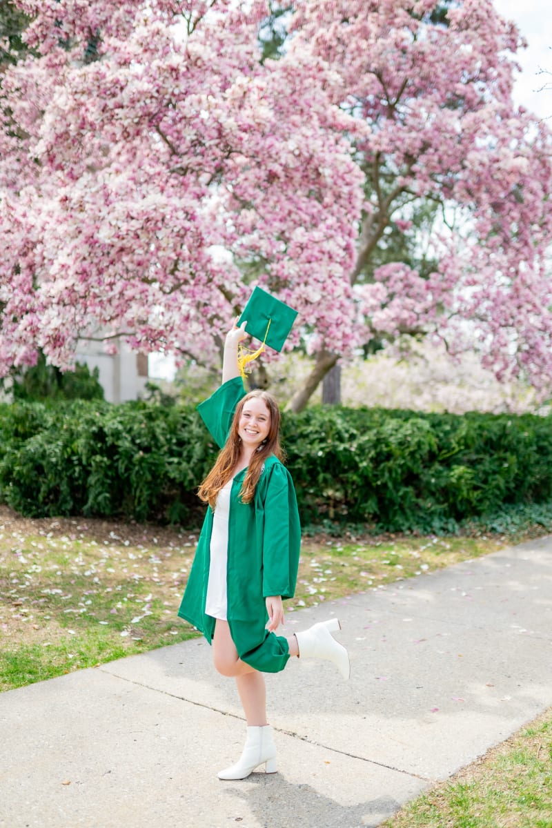 MSU graduate tossing her cap in spring blossoms