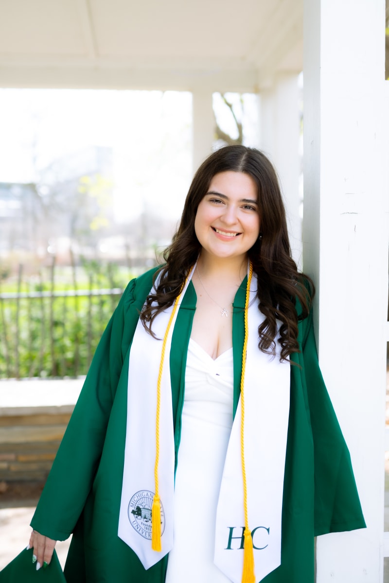 MSU graduate in cap and gown at a doorway