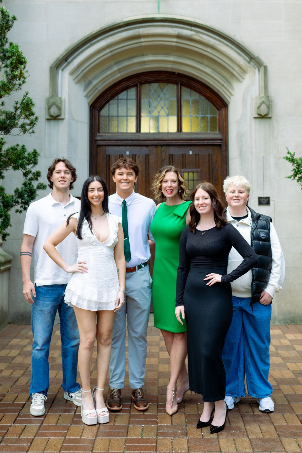 Family of six together at a campus archway
