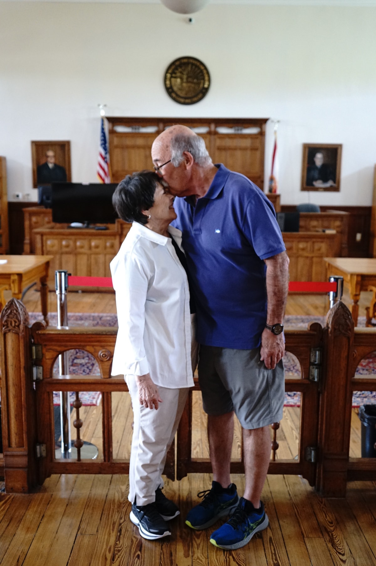 Couple sharing a forehead kiss in a historic courtroom