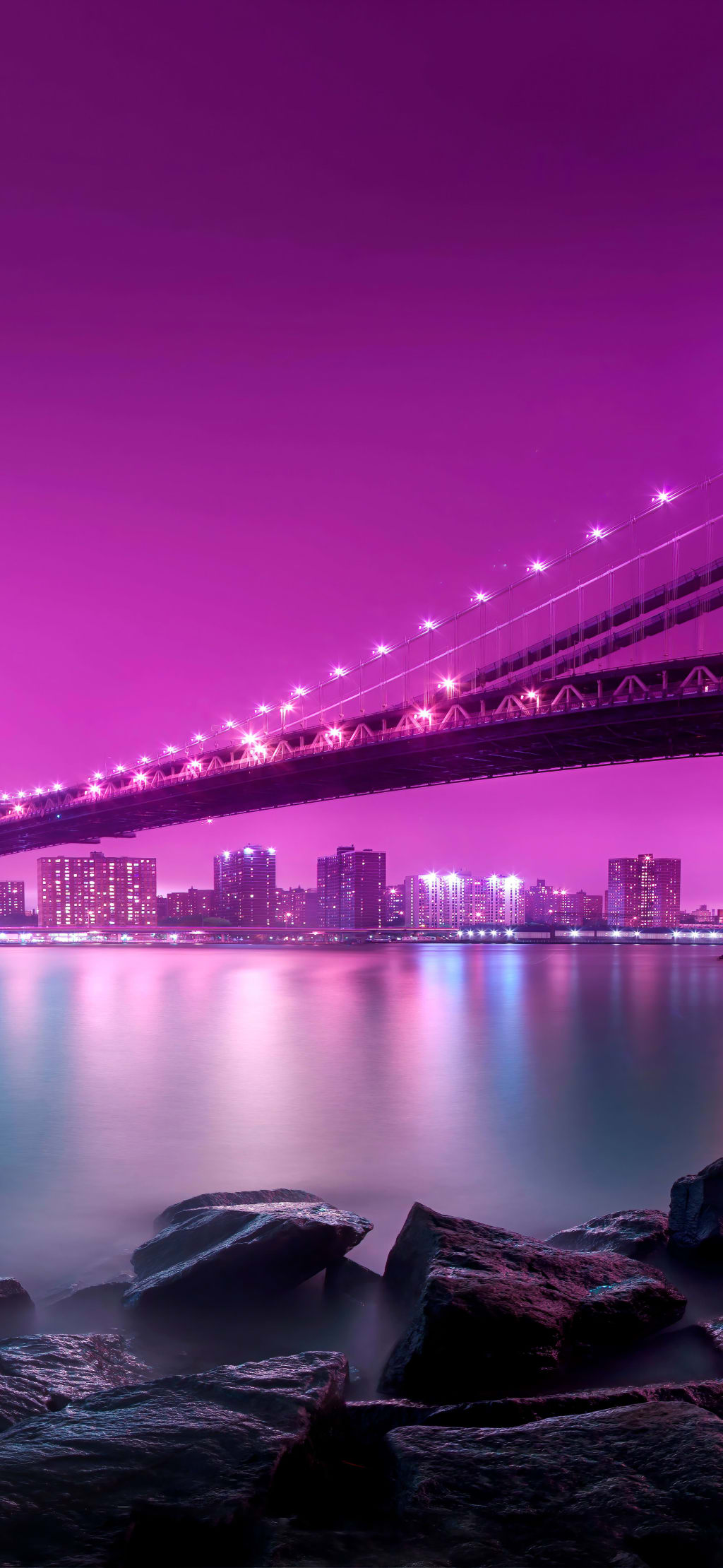Illuminated bridge spanning glowing magenta cityscape with reflections on water and dark rocks below, neon-lit urban skyline