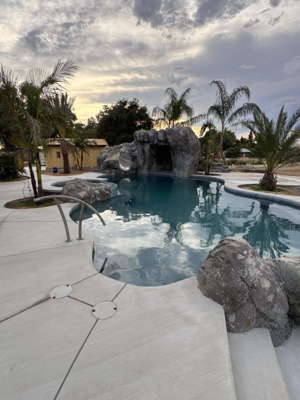 Keeler – rock grotto pool with waterfall slide at sunset