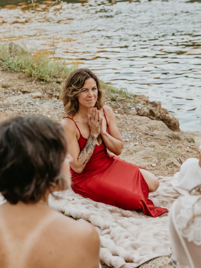Woman in a red dress with prayer hands during a breathwork and cacao ceremony