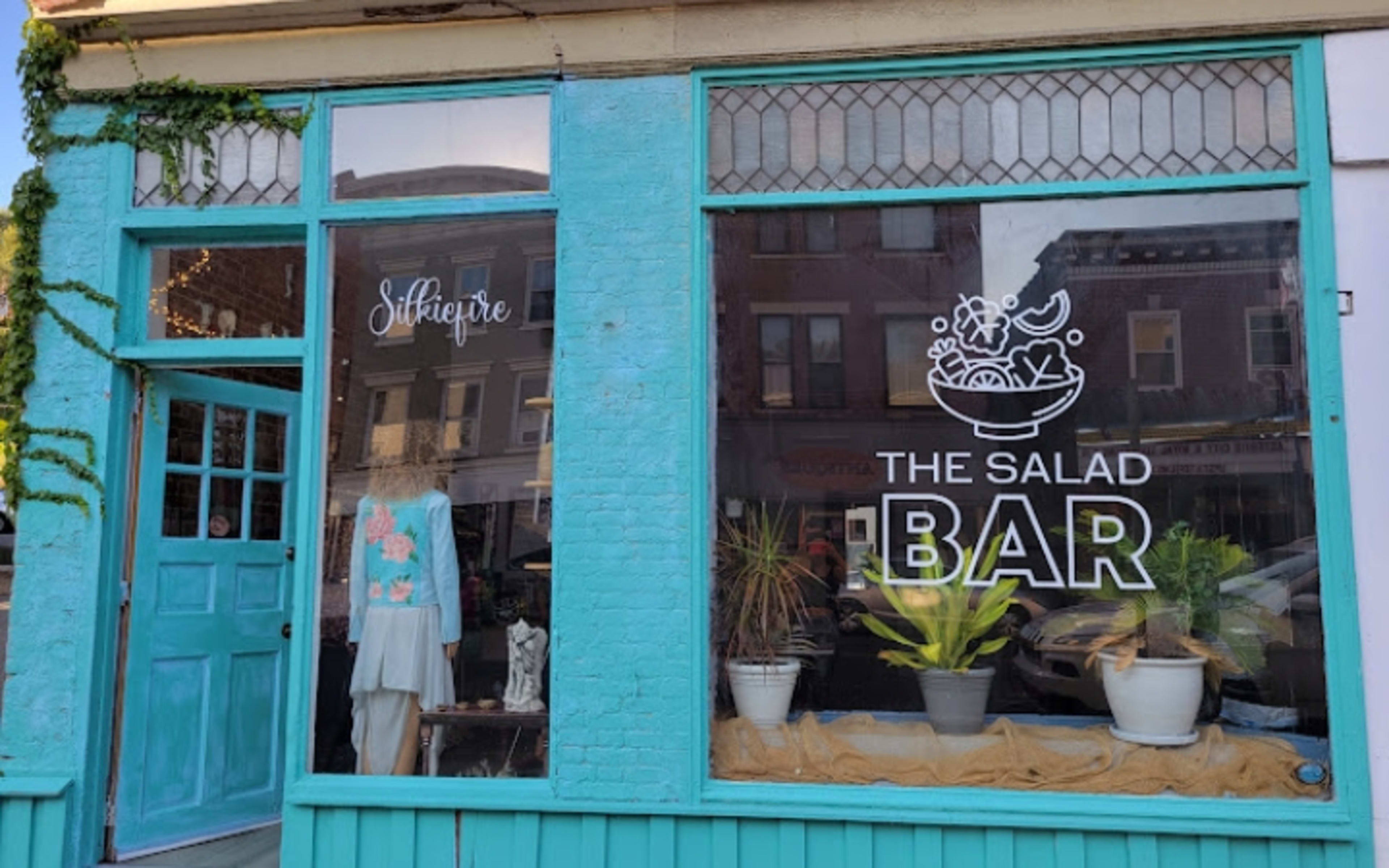 Turquoise storefront of The Salad Bar restaurant with large windows and signage in Greene County.