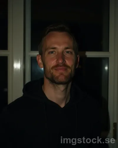 Medelålders man i hoodie vid fönster på kvällen