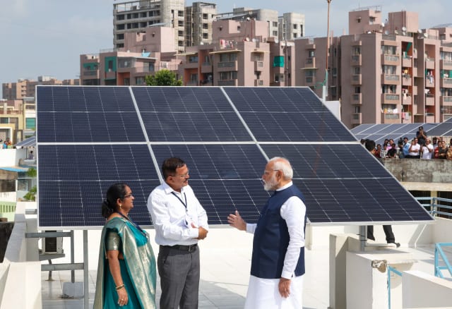 Prime Minister Narendra Modi interacting with beneficiaries of the PM Surya Ghar Muft Bijli Yojana during a public event.