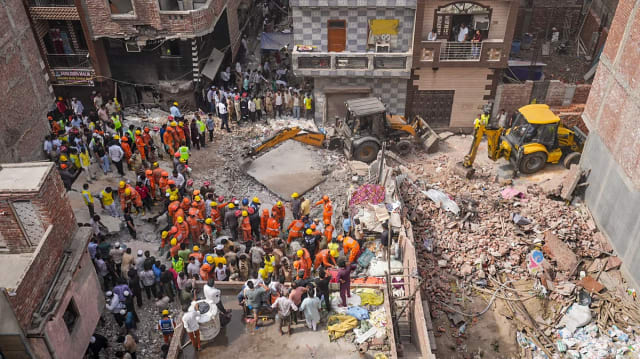 Rescue teams search through debris after a building collapsed in Delhi's Satya Niketan area.
