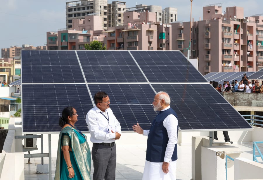Prime Minister Narendra Modi interacting with beneficiaries of the PM Surya Ghar Muft Bijli Yojana during a public event.