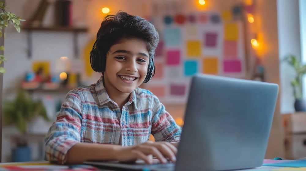 smiling-boy-with-headphones-working-laptop
