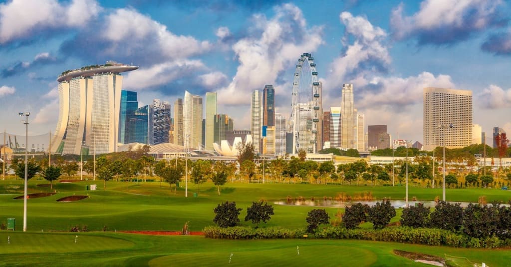 Stunning view of Singapore's skyline including Marina Bay Sands and a lush golf course in the foreground.