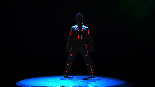 LED Show: A dancer with leds all over his body stands in a dark room