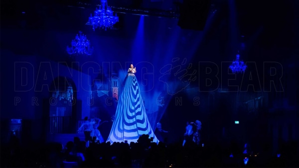 Female Singer is flying over the stage and wearing a five meter long dress. A pattern is projected onto the dress.   