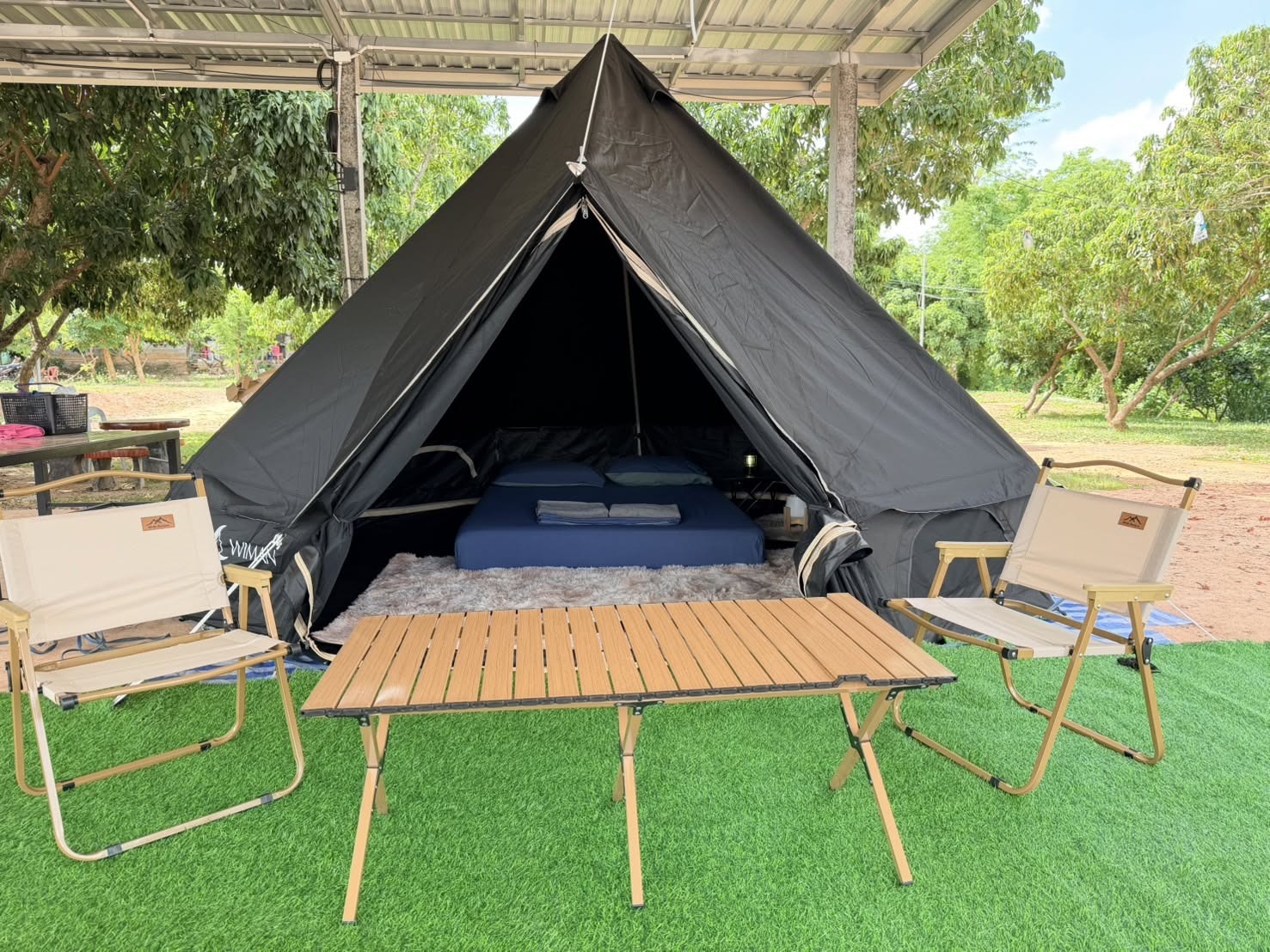 เต็นท์กระโจมสีดำไร้เสากลาง bell tent wiman - ทางเข้าเต็นท์กระโจมที่เปิดกว้าง เผยให้เห็นพื้นที่นั่งเล่นด้านในบนสนามหญ้าเทียม