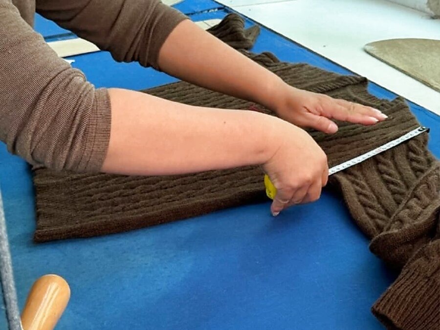 Quality control technician measuring a finished knitwear garment