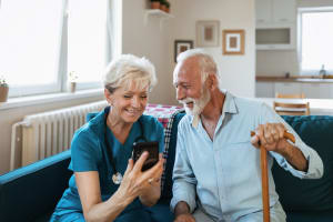 nurse ander gentleman looking at phone screen in home care setting