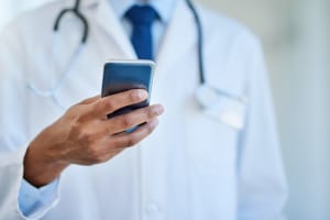 Closeup shot of an unrecognizable doctor using a cellphone in a hospital