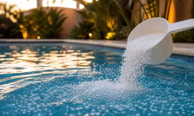 Granular pool shock dissolving in the deep end of a backyard swimming pool at dusk