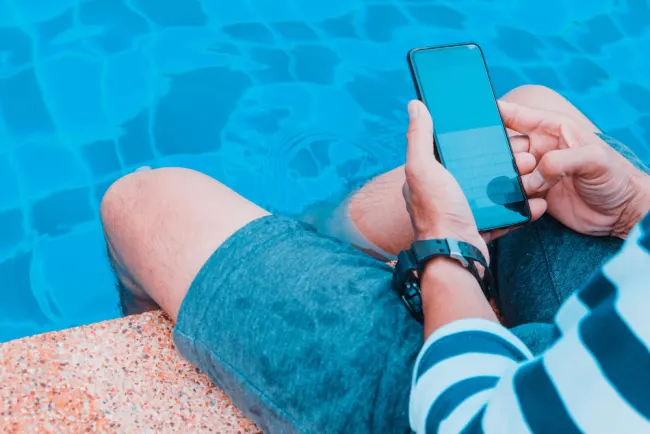 Man soaking in pool with phone