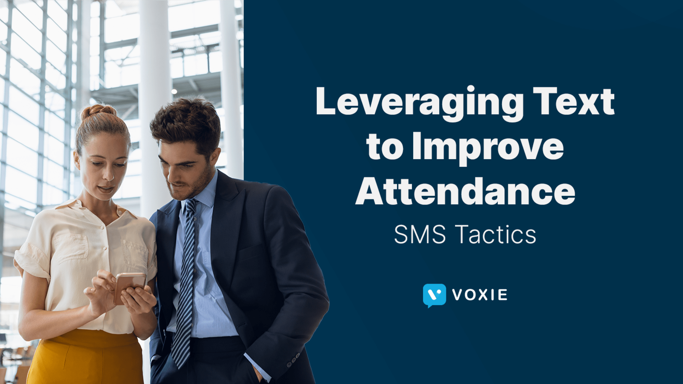 Two colleagues look at a phone, likely thinking how they can leverage texting to improve attendance.