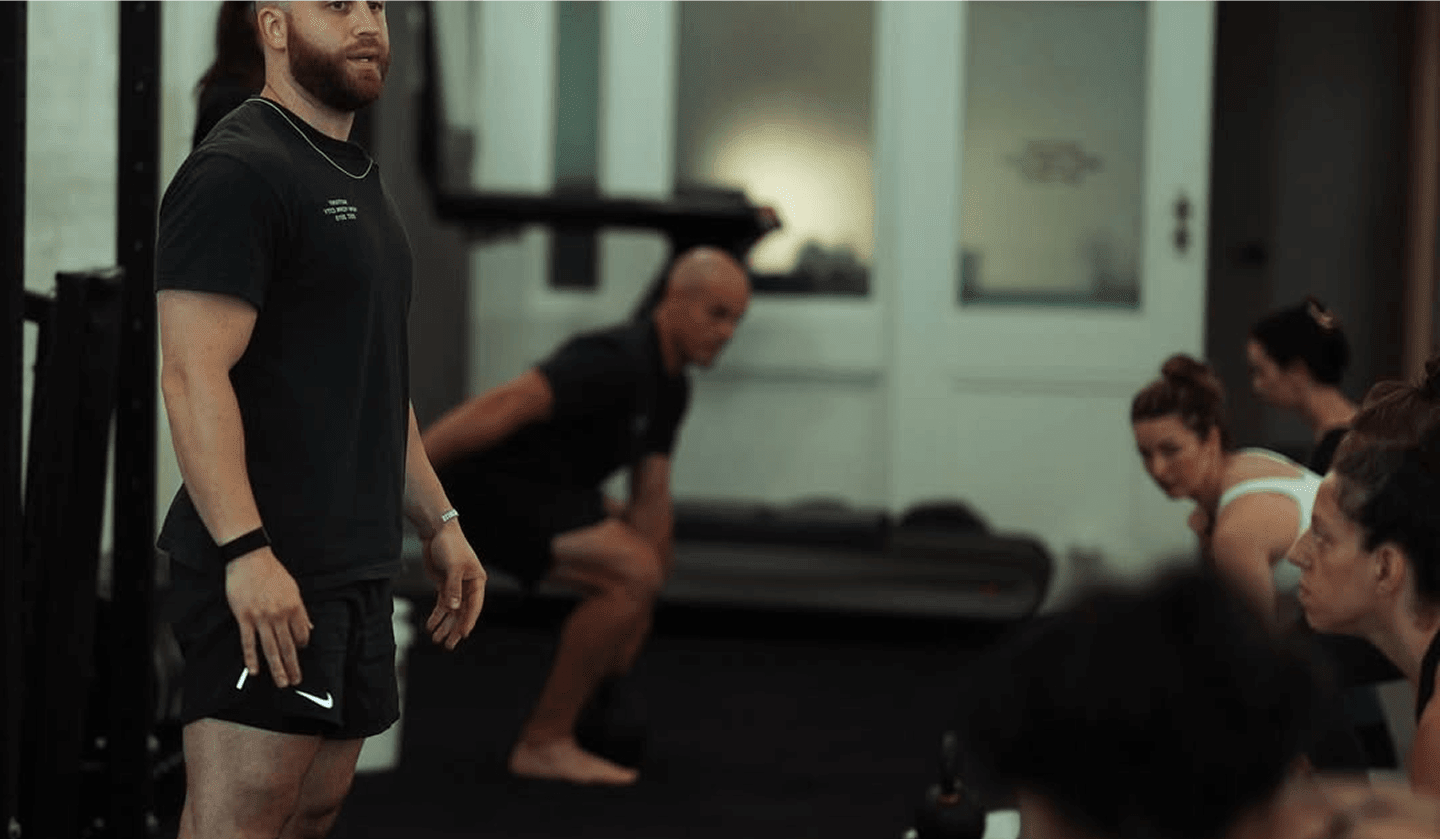 Hero image of a fitness coach training his client with kettlebells in a gym