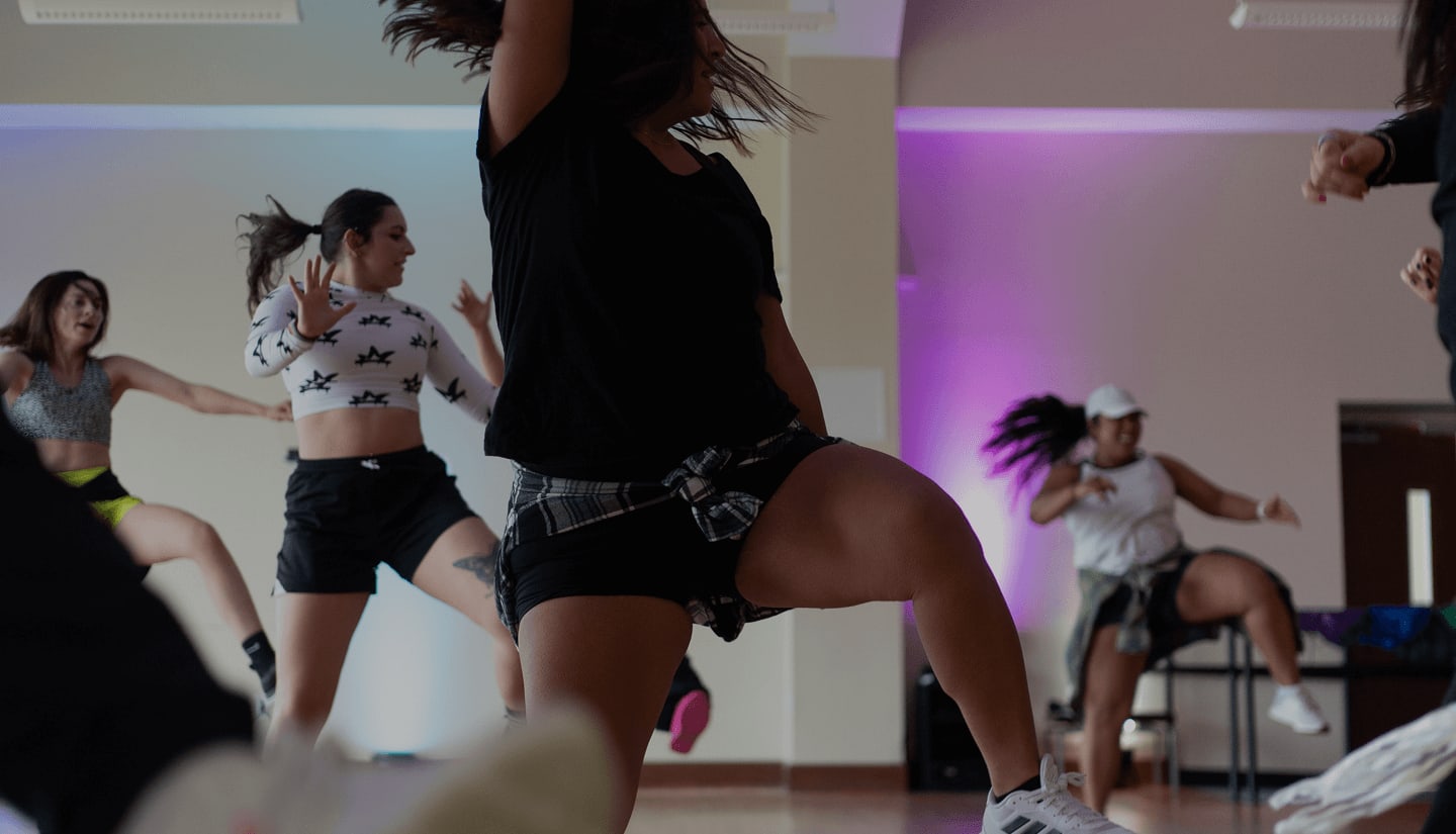 Hero image of a fitness clients in a group training class engaging in a dance cardio workout