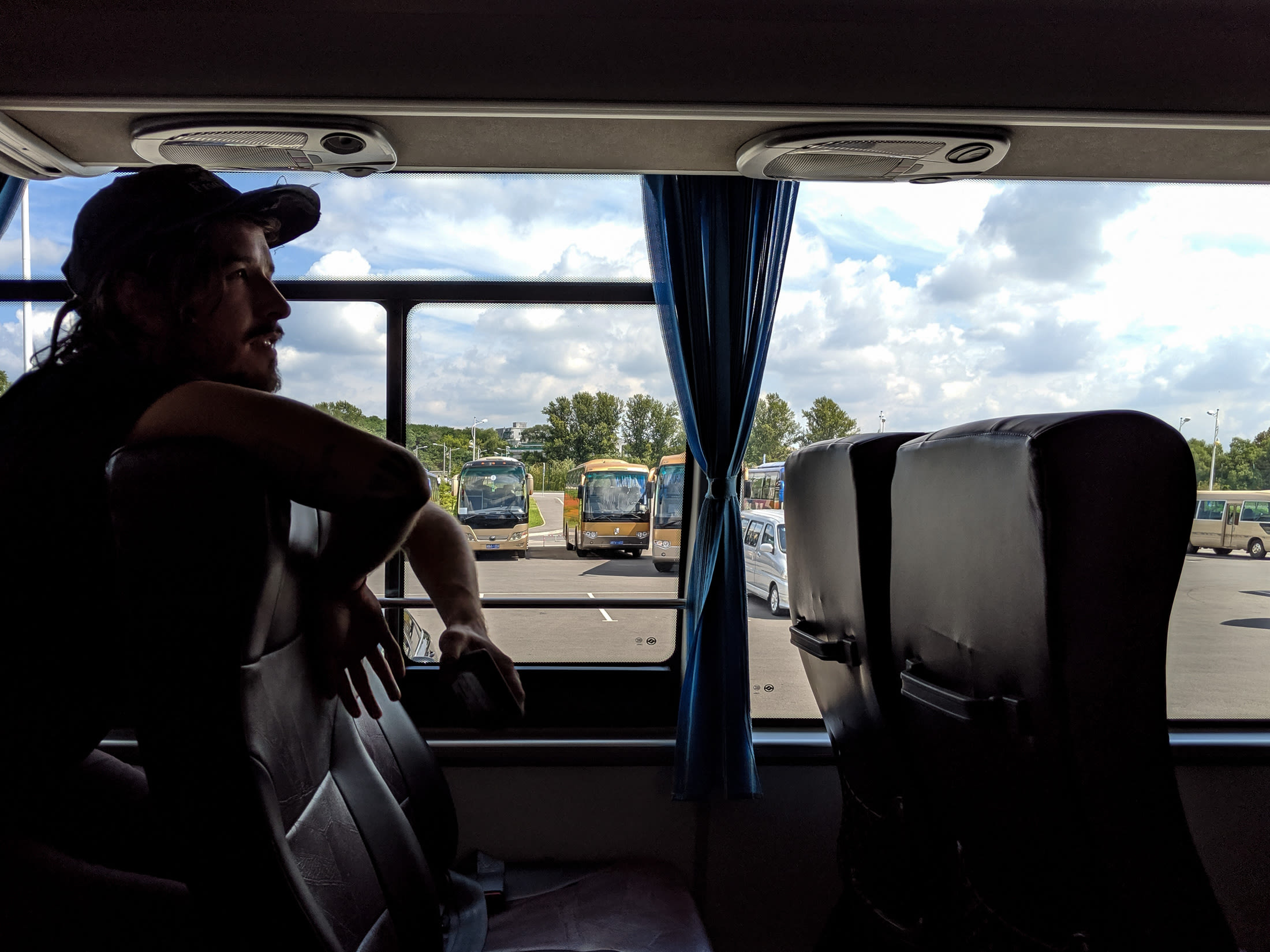 A side-view of a North Korean tour bus darkly lit with someone leaning over the seat.
