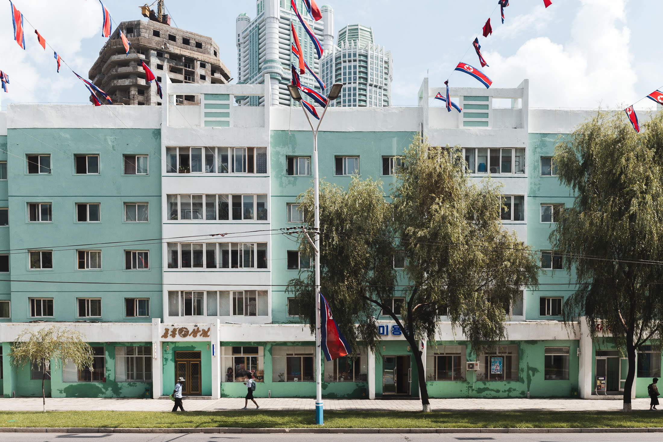 Main street of a pastel colour buildings, trees and flags.