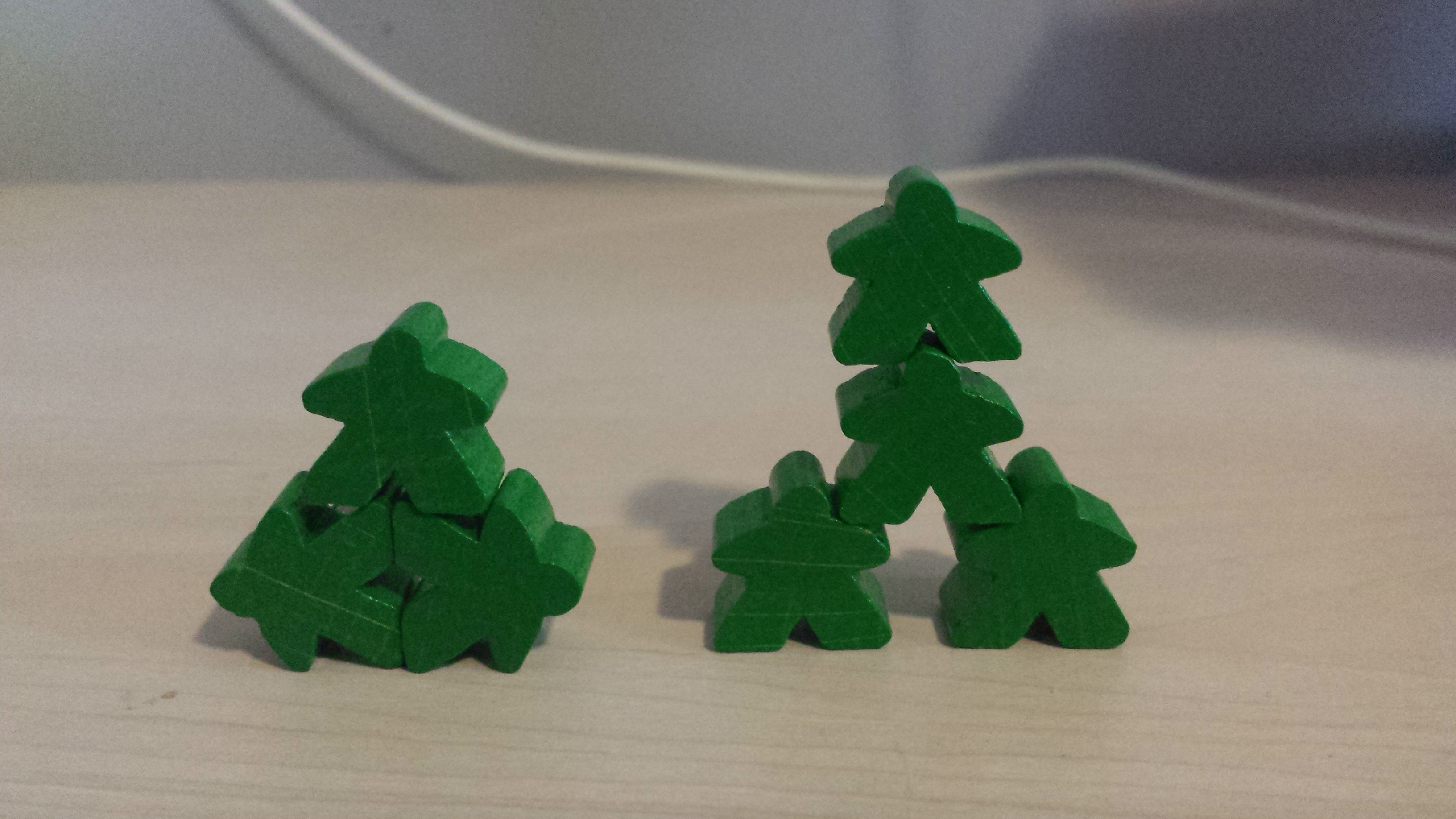 The humble meeple — Carcassonne introduced most of us to them A small stack of green Carcassonne meeples balanced on the table