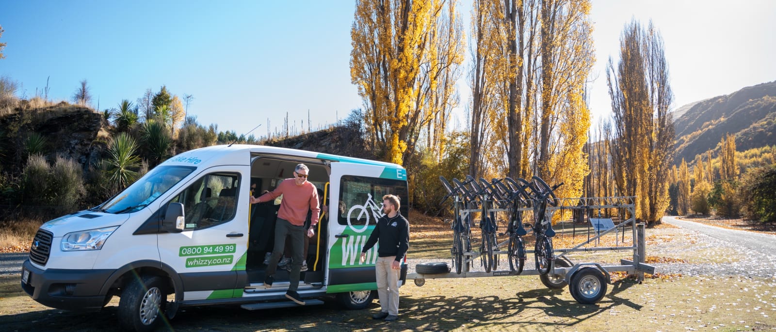 Whizzy shuttle van with the bike trailer pulled up at the Gibbston trailhead under autumn poplars