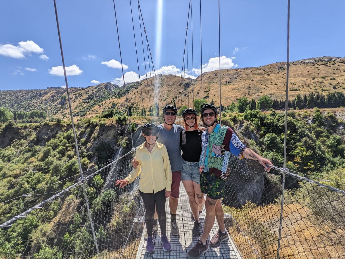 Four riders posing on a swing bridge above the Kawarau gorge