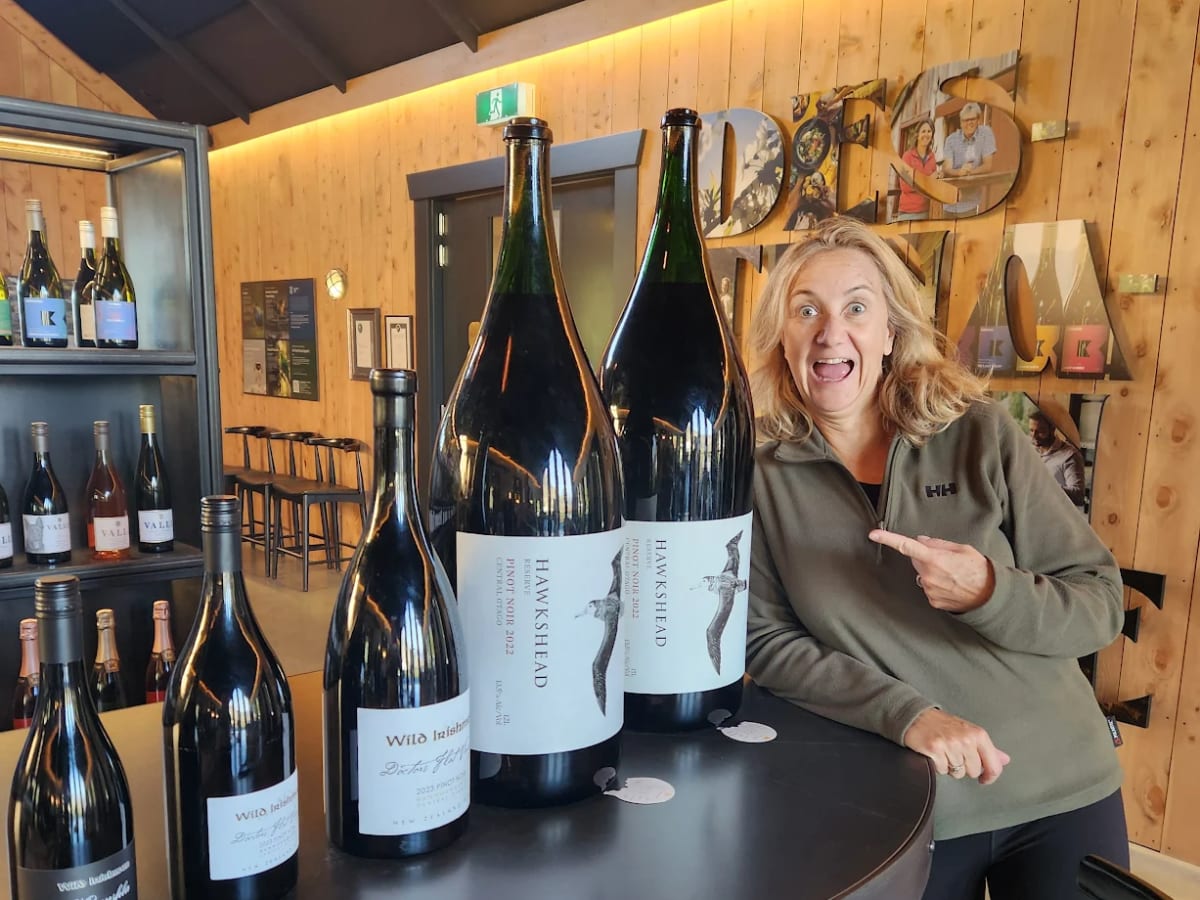 Customer pointing at giant wine bottles in a Gibbston cellar door