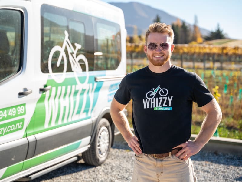Whizzy driver standing in front of the branded shuttle van ready for morning pickup