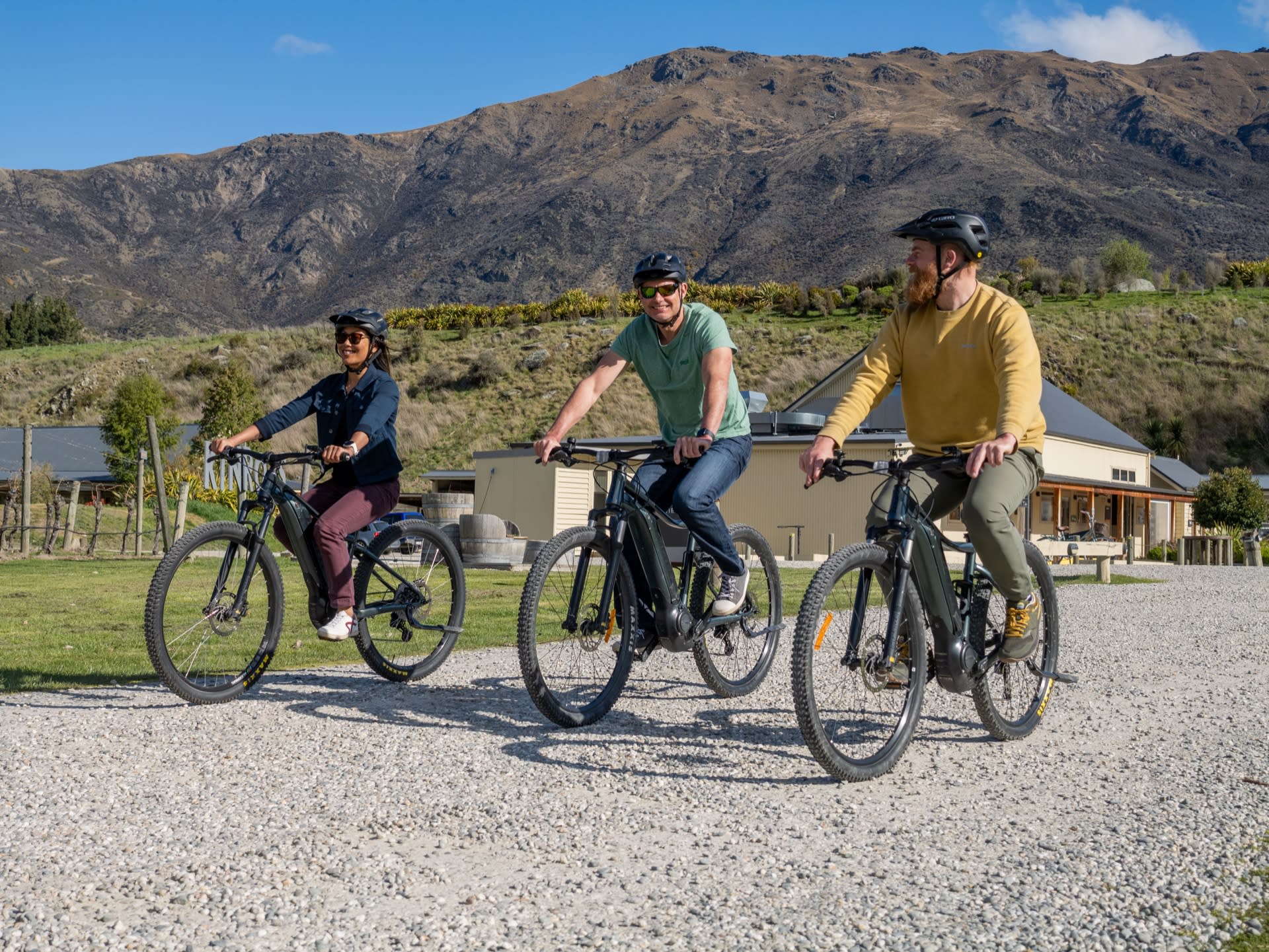 Three friends riding e-bikes past Queenstown vineyards