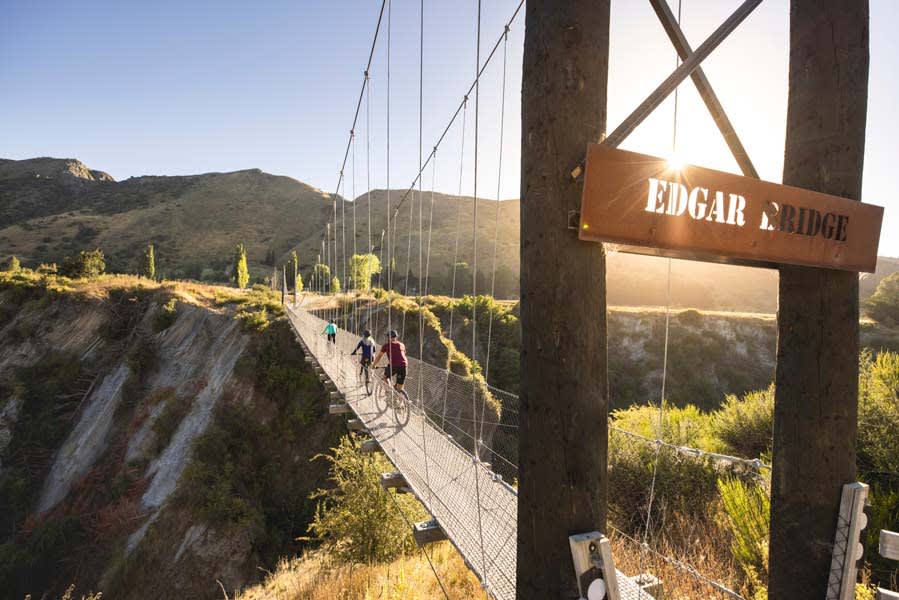 Cyclists crossing the Edgar Suspension Bridge over the Arrow Gorge