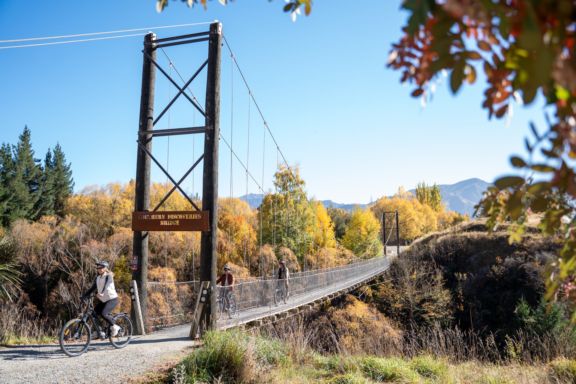 Rider passing the Southern Discoveries Bridge sign on the Arrow Bridges Trail in autumn