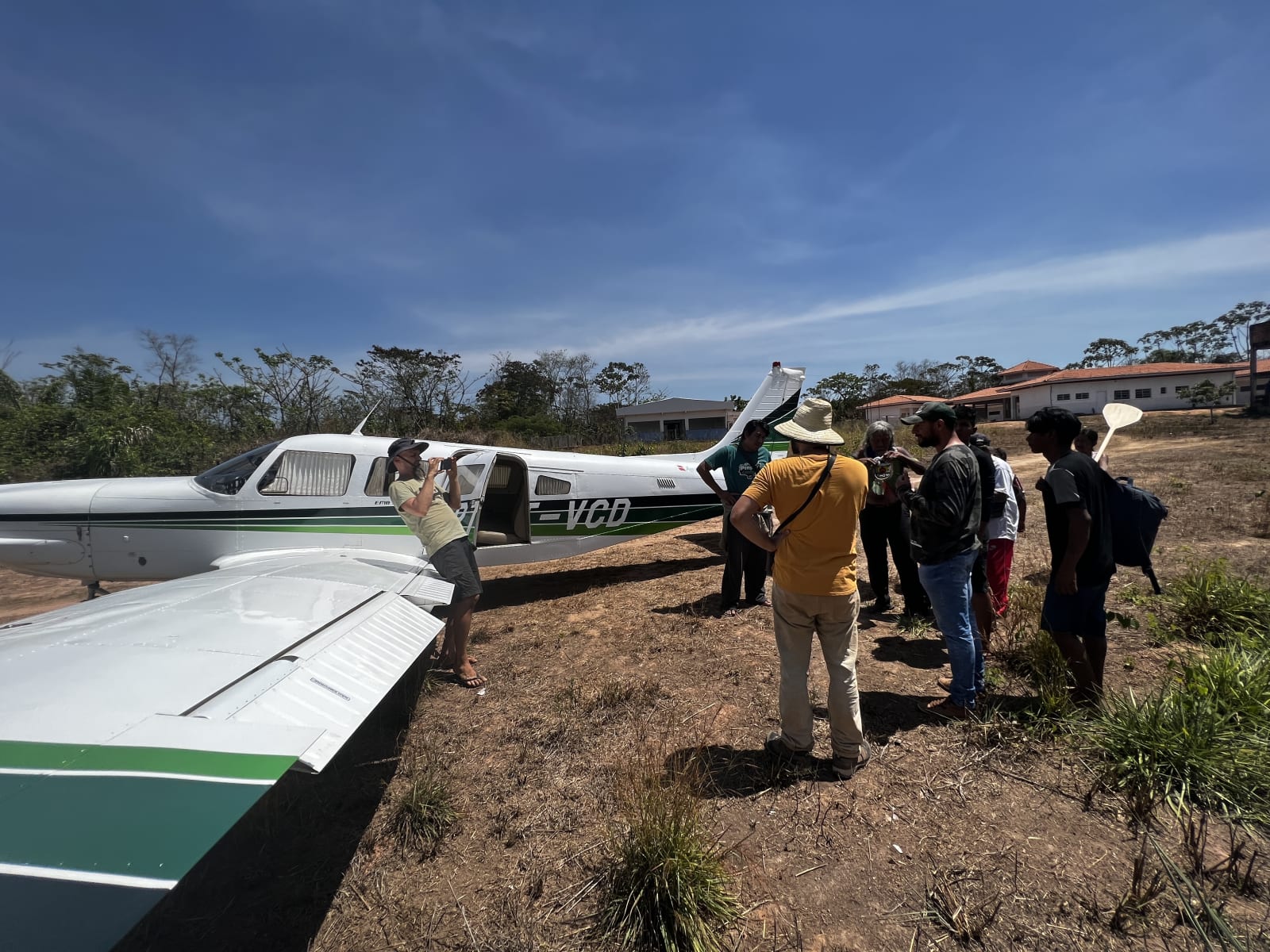 A small bush plane being loaded with people and camera cases on a grass strip