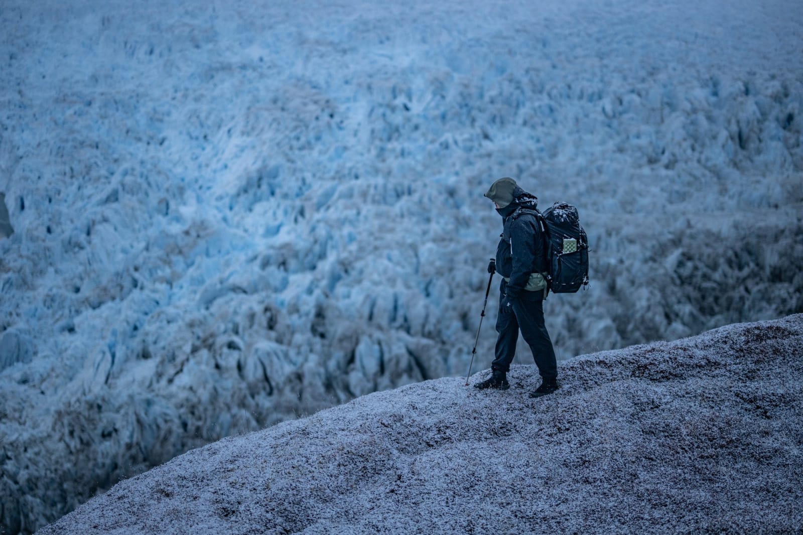Filmemacher auf einem gefrorenen Grat vor der Eiswand des Eqi Gletschers, Grönland