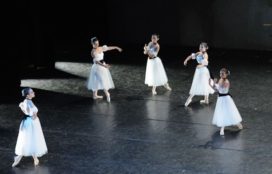 Five girls are dancing ballet on a black stage dressed in white, ballet show, ensemble