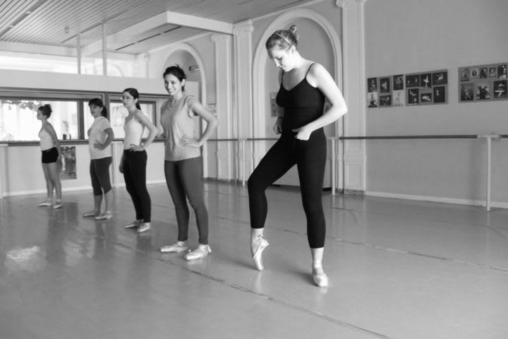 A female ballet ensemble is practicing in a black and white setting, ballet_practice_improvement_patience