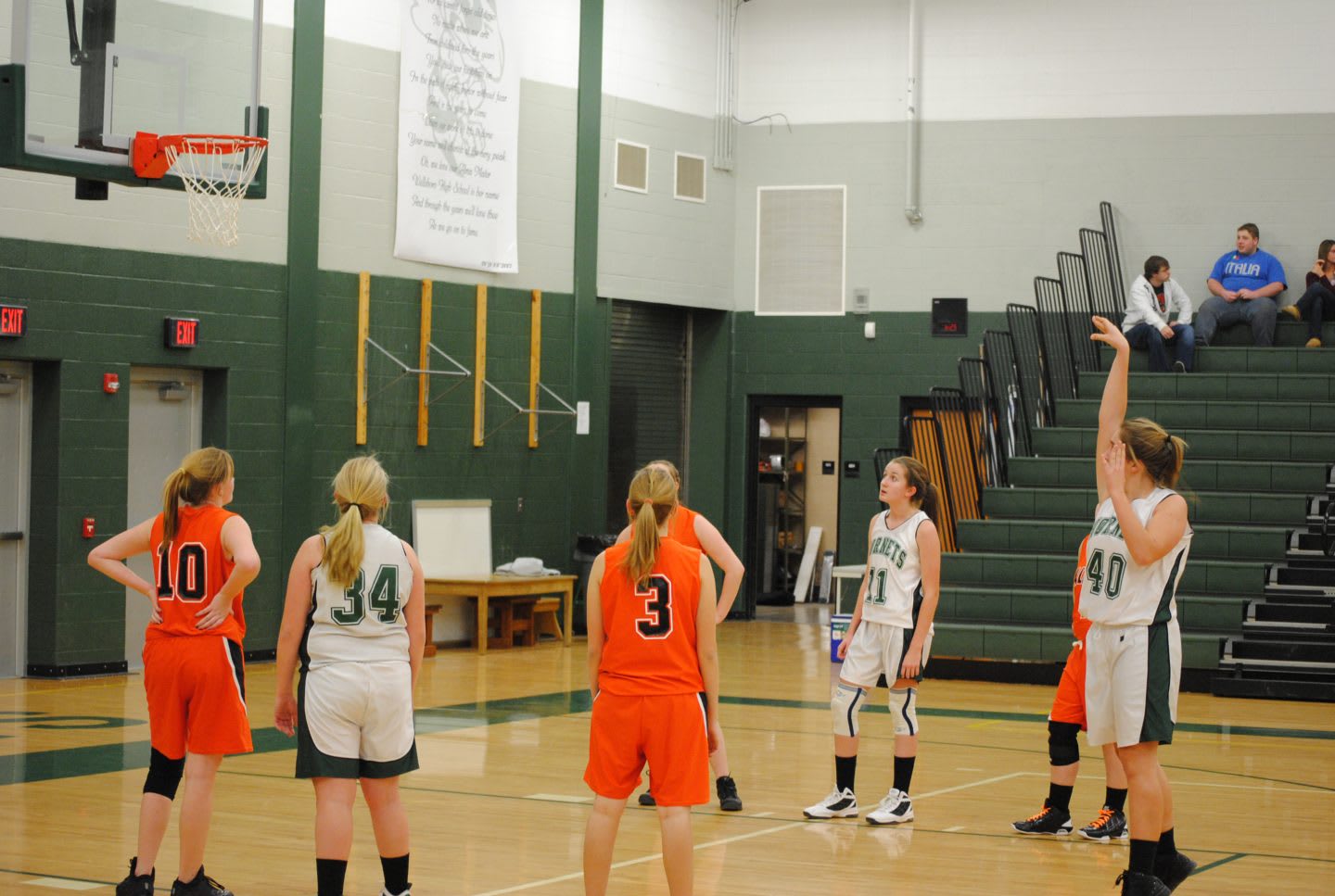 A female basketball team is playing and one girl is at the free throw line throwing the ball to the basket, team sport, winning, motivation