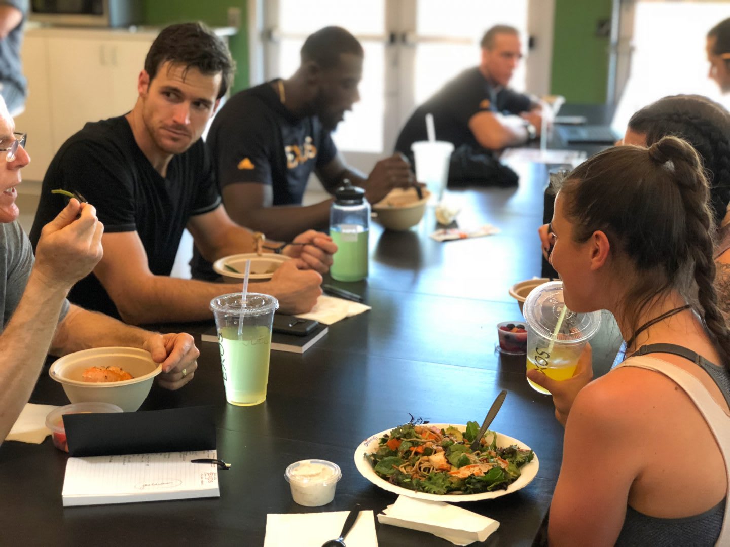 Colleagues having lunch together to prepare a training session with exos on a huge table_ team work
