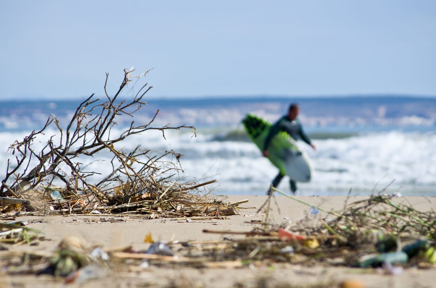 Looking at a beach with a surfer running in the background_ Photo of blurred beach_ trash_pollution_activist