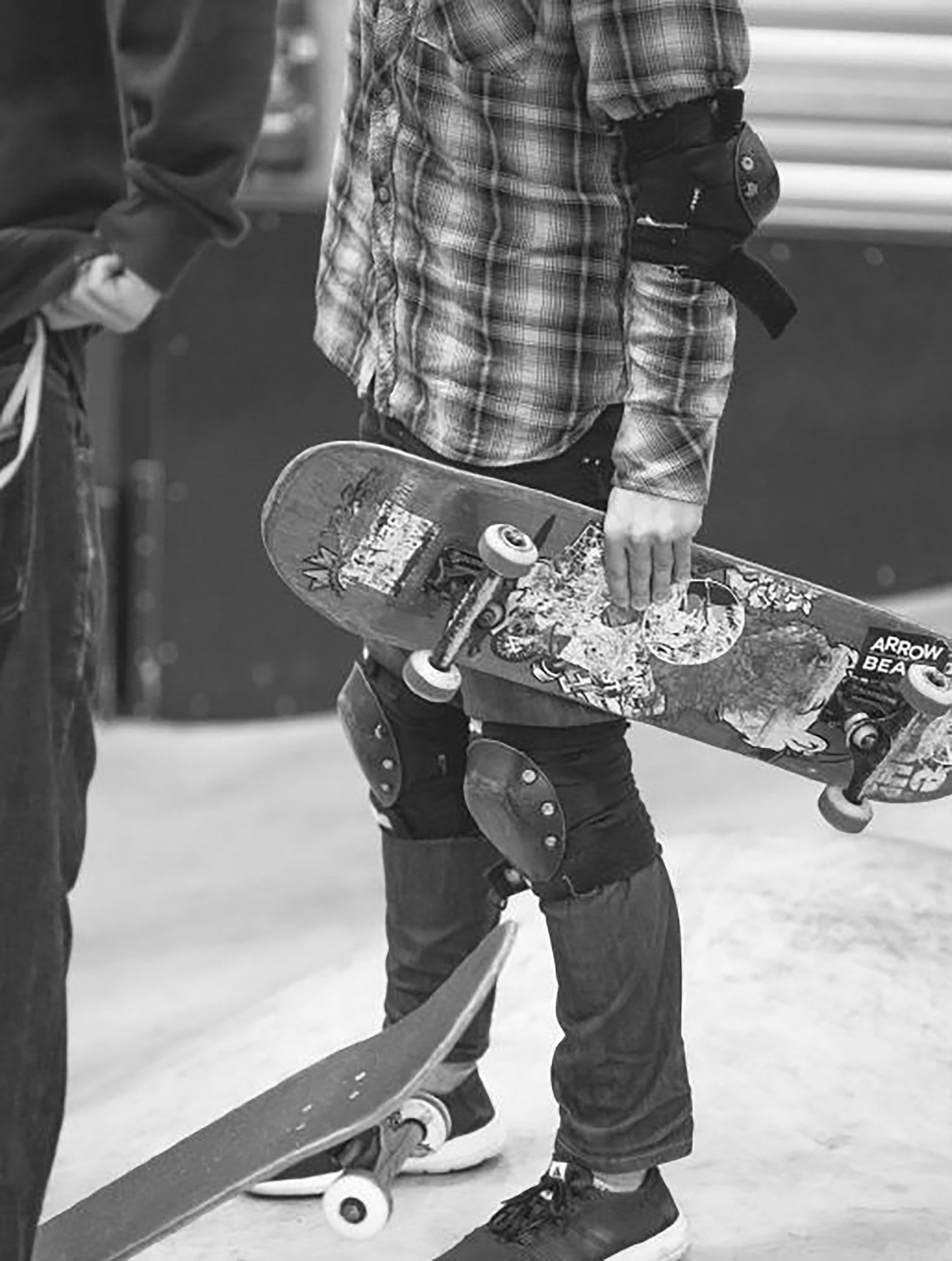 Black and white photo of a skater boy wearing protective knee and elbow pads getting ready to skate. skater, determination, skateboard, hobbies.,