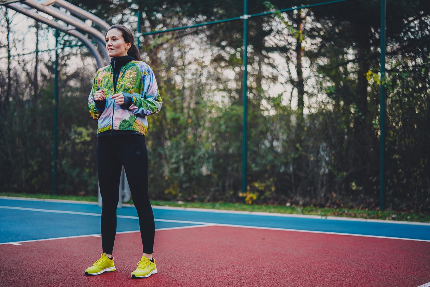 A woman wearing fitnss clothing stands tall in a tennis court with her held up under her chest. sport, fitness, training, thinking.